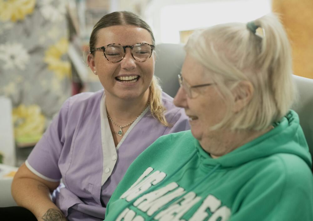 A carer and a resident laughing together